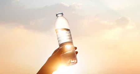Regenwasser trinken: Jemand hält eine Flasche mit Wasser in Richtung Himmel