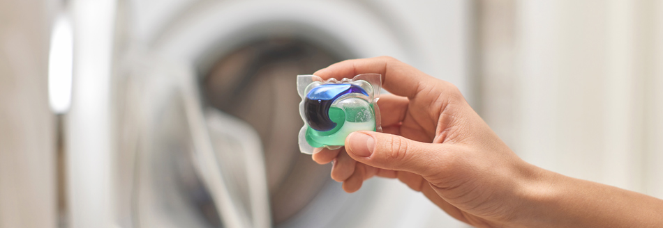 Waschmittel: Jemand gibt einen Geltab bzw. Pod in die Waschmaschine