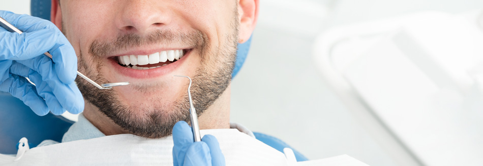 Ein Mann mit weißen Zähnen lacht der zahnmedizinischen Behandlung entgegen