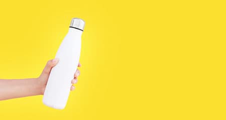 Flaschen reinigen mit Gebissreiniger: Eine weiße Flasche vor gelbem Hintergrund