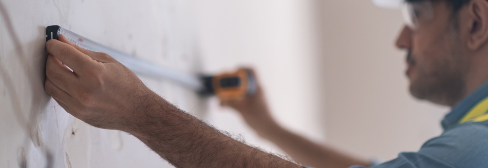 Ein Mann misst die Entfernung zweier Bohrlöcher aus.