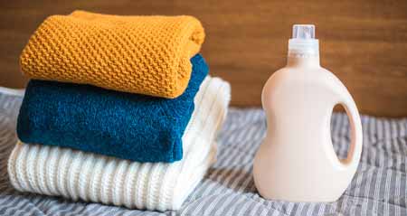 Wollwaschmittel: Wollpullover liegen neben Waschmittel