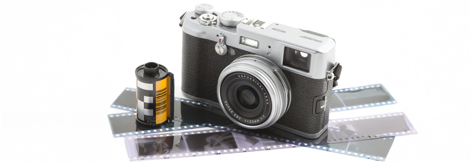 Eine alte Fotokamera steht neben einer Filmrolle und auf Negativen