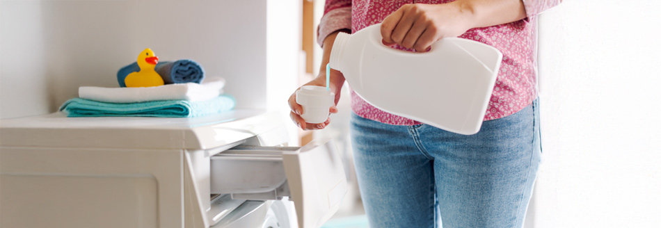 Flüssigwaschmittel: Eine Person füllt Flüssigwaschmittel in eine Waschmaschine