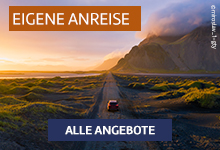 Ein Auto fährt auf einer einsamen Straße durch eine weitläufige Landschaft bei Sonnenuntergang.