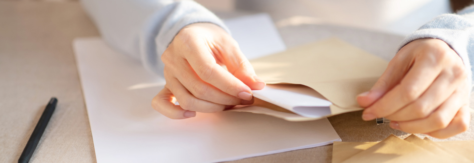 Eine Frau steckt ein Schreiben in einen Briefumschlag.
