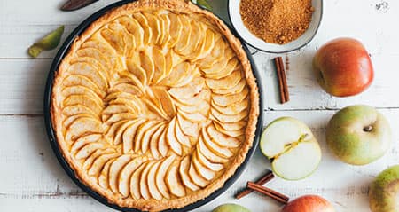 Welche Äpfel für Apfelkuchen? Ein gebackener Kuchen steht neben einigen Äpfeln und Zimt