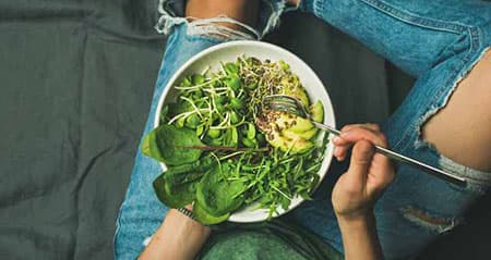 Eine Frau isst Salat am Abend