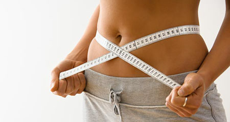 BMI Body-Mass-Index: Eine Frau misst den Taillenumfang