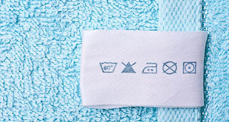 An einem blauen Handtuch ist ein Etikett mit Waschsymbolen angebracht