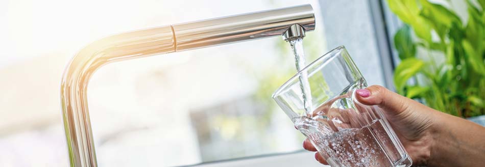 Jemand füllt warmes Wasser in ein Glas