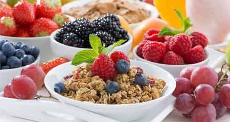Ein gedeckter Frühstückstisch mit Müsli, Beeren und Trauben