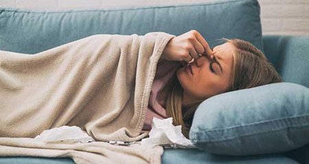 9 Tipps gegen Infektionen: Eine Frau liegt mit einem Infekt auf der Couch