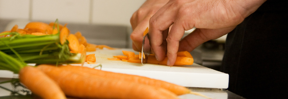 Verfärbtes Plastik: Jemand schneidet eine Karotte auf einem hellen Brett