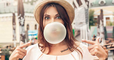 Kaugummi verschluckt: Eine Frau bläst eine große Kaugummiblase