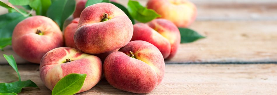 Ziemlich platte Plattpfirsiche liegen auf einer Holzfläche und warten darauf, gegessen zu werden.