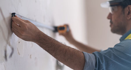 Ein Mann misst die Entfernung zweier Bohrlöcher aus.