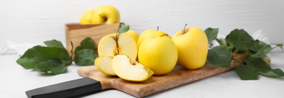 Ein paar Golden Delicious liegen essbereit auf einem Holzbrett. Greif zu!