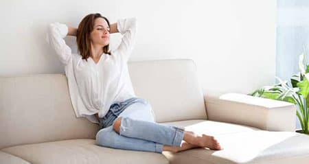 5 Tipps gegen Rauchgeruch: Eine Frau sitzt auf der Couch