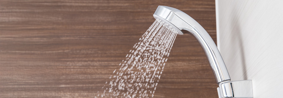 Ein Duschkopf lässt Wasser in die Dusche plätschern.