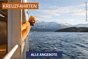 Ein Mann lehnt lächelnd am Schiffsgeländer und blickt über ein Fjordpanorama mit Bergen.