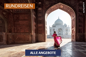 Frau in farbenfroher Kleidung im Torbogen eines historischen Gebäudes mit Blick auf den Taj Mahal.