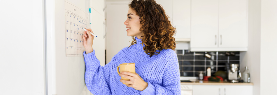 Feiertage 2029: Eine junge Frau notiert etwas in einem Wandkalender