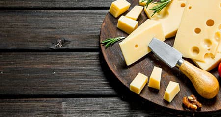 Ist Käse vegetarisch? Aufgeschnittener Käse liegt auf einem Holzbrett