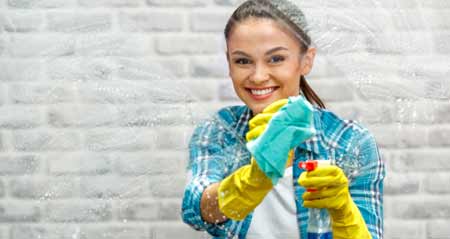 Eine junge Frau putzt ein Fenster