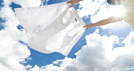 Feinwaschmittel: Eine Bluse flattert vor blauem Himmel im Wind