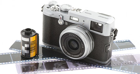 Eine alte Fotokamera steht neben einer Filmrolle und auf Negativen