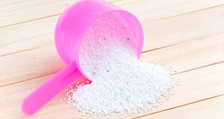 Vollwaschmittel: Eine Dosierhilfe mit Waschpulver liegt auf Holz