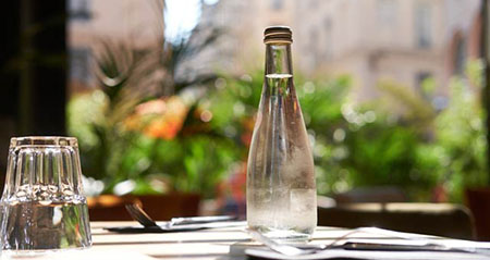 In einem Restaurant steht eine Flasche Mineralwasser auf dem Tisch