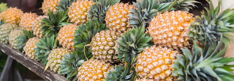 Mehrere Ananas liegen an einem Verkaufsstand und warten auf Naschwillige